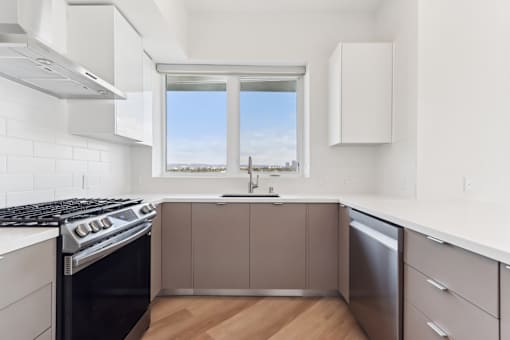 A modern kitchen with a stove, sink, and window.