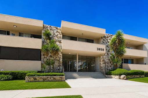 A modern building with stone pillars and a clear blue sky in the background.