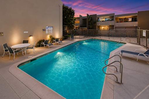 A swimming pool surrounded by chairs and a fence.
