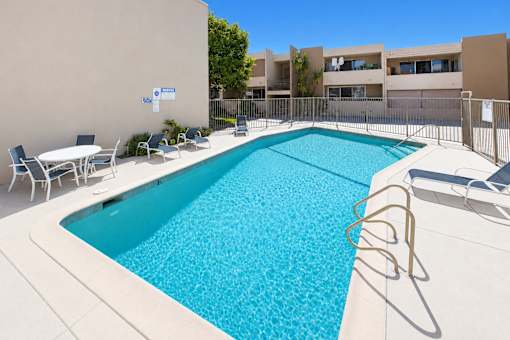 A swimming pool with a white fence and chairs around it.