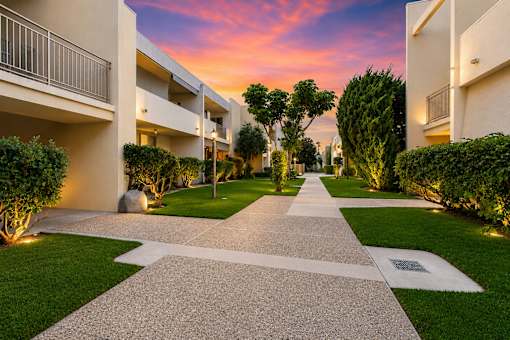 A pathway leads through a grassy area between two buildings.