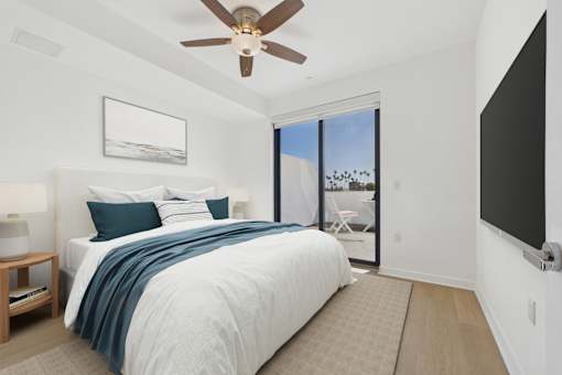 A bedroom with a bed, a ceiling fan, and a painting on the wall.