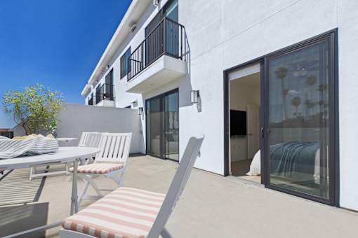A patio with a table and chairs is in front of a white building.