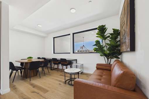 A brown leather couch sits in a room with a table and chairs.