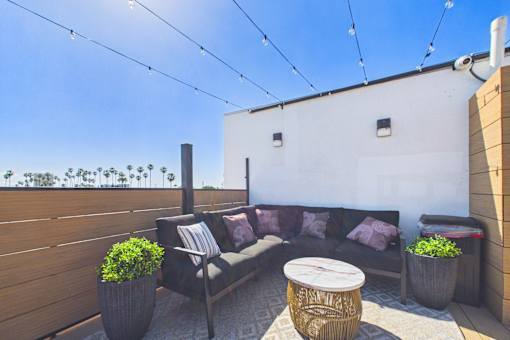 A patio with a couch, table, and potted plants.