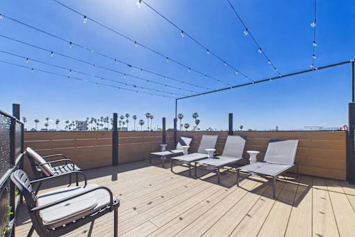 A wooden deck with chairs and a table is covered with string lights.