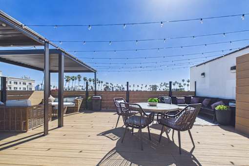 A patio with a table and chairs under a canopy with lights strung up.