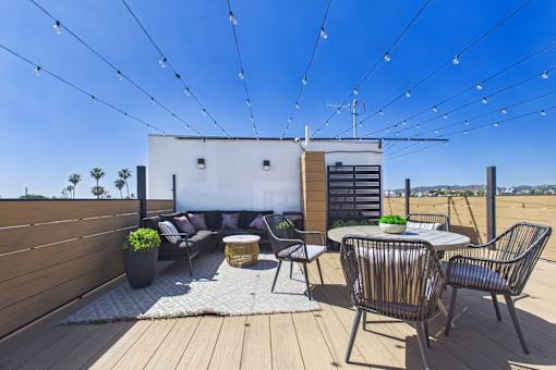 A patio with a table and chairs is set up on a wooden deck.