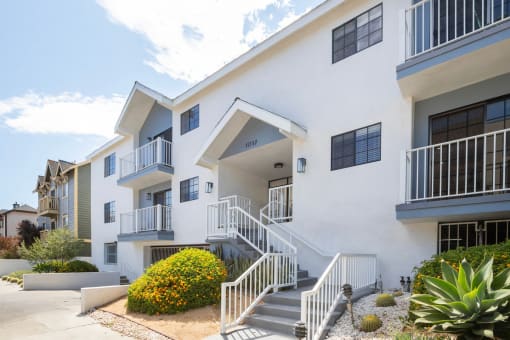 a white apartment building with stairs and a sidewalk