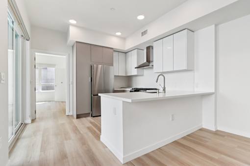A kitchen with white cabinets and a wooden floor.