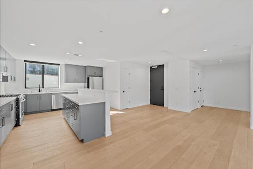 A modern kitchen with wooden floors and stainless steel appliances.