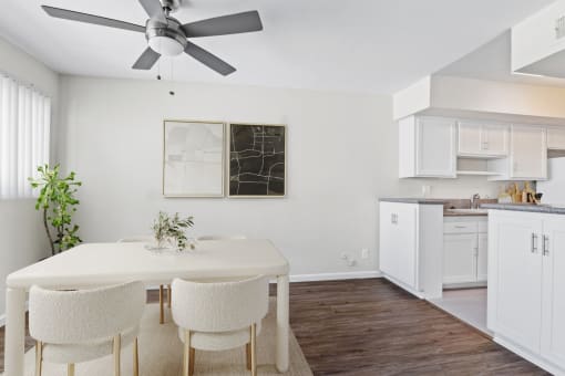 a kitchen and dining room with white cabinets and a ceiling fan