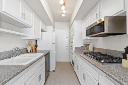 a kitchen with white cabinets and granite counter tops and a stove and microwave