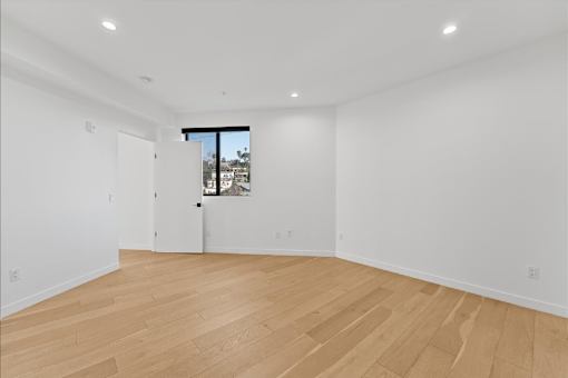 A room with wooden flooring and a window overlooking a cityscape.