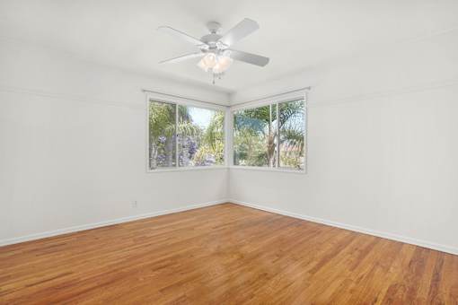 A room with a ceiling fan and a window showing a view of trees.