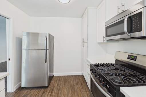 A kitchen with a stainless steel refrigerator, a microwave, and a gas stove.