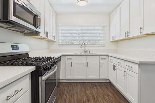 A kitchen with white cabinets and a black stove top oven.