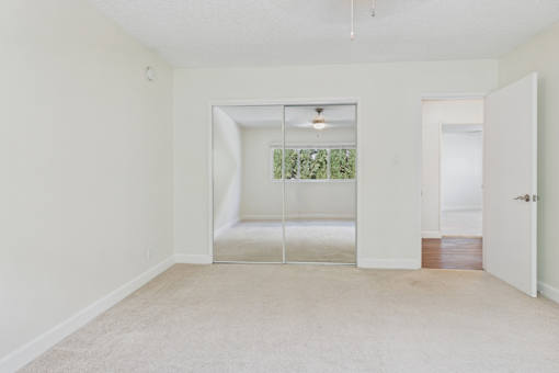 A room with a carpeted floor and a ceiling fan.