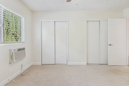 A room with three white doors and a window with blinds.