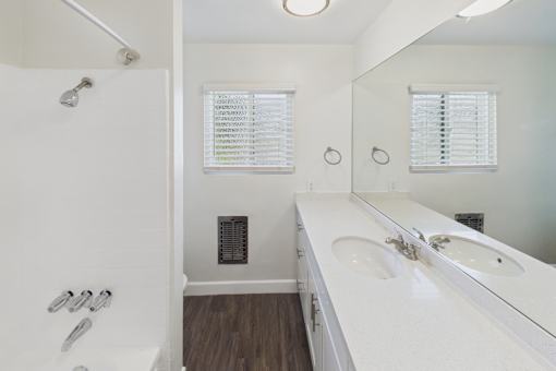 A white bathroom with a sink, mirror, and shower.