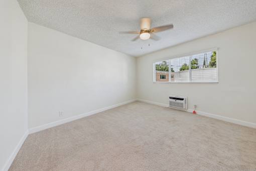 A room with a ceiling fan and carpeted floor.