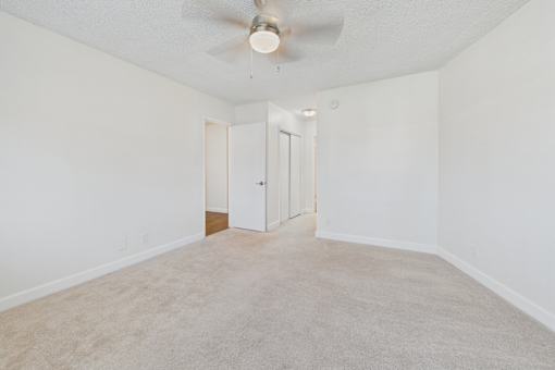 A room with a ceiling fan and carpeted floor.
