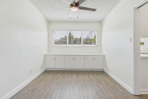 A room with a ceiling fan and a window with blinds.