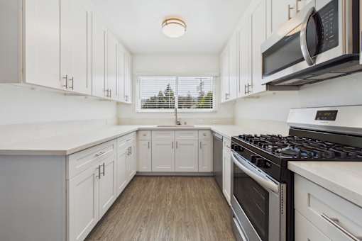 A kitchen with white cabinets and a black stove top oven.