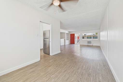 A room with a ceiling fan and a refrigerator.