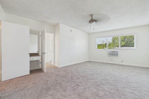 A room with a carpeted floor and a ceiling fan.