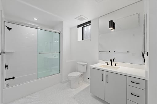 A white bathroom with a toilet, sink, and shower.