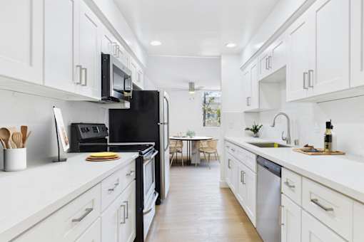 A modern kitchen with white cabinets and a black refrigerator.