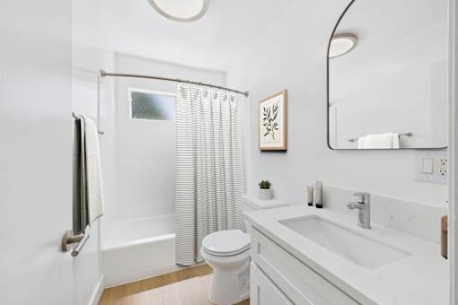 A white bathroom with a toilet, sink, and shower.