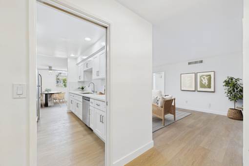 A kitchen with white cabinets and a dining table with chairs.