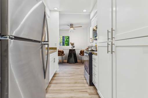 A modern kitchen with a stainless steel refrigerator and white cabinets.