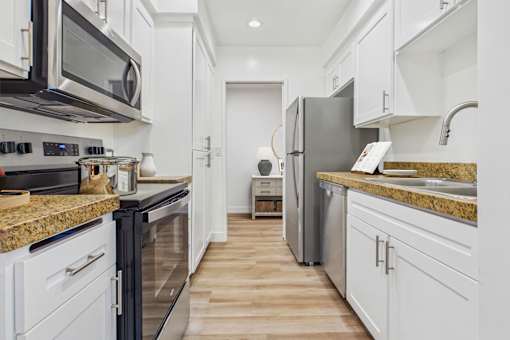 A kitchen with black and white appliances and wooden floors.