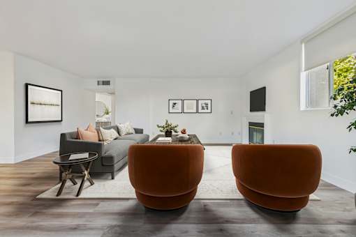 Two orange chairs are placed in a room with a grey couch and a coffee table.