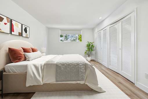 A bedroom with a bed, pillows, and a plant.