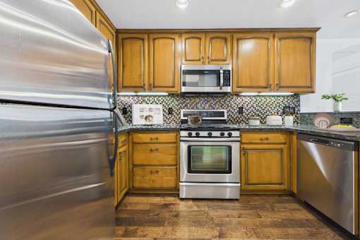 A kitchen with wooden cabinets and a stainless steel refrigerator.