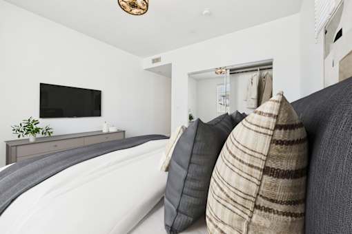 A living room with a grey couch and a flat screen TV mounted on the wall.