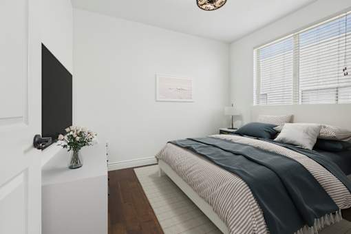 A bedroom with a bed, a television, and a vase of flowers.