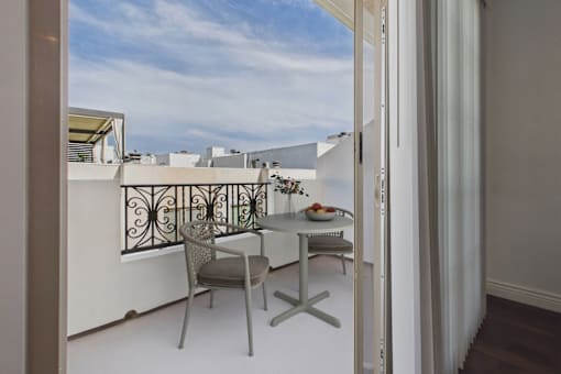 A balcony with a table and chairs overlooking a cityscape.