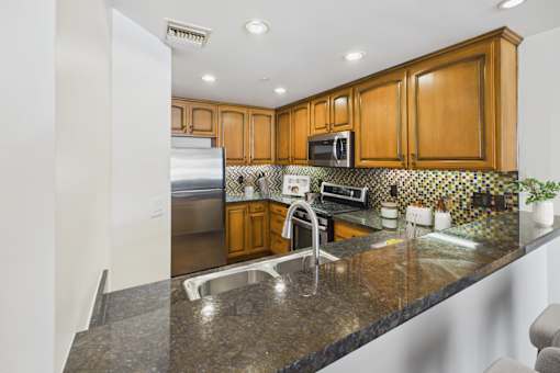 A kitchen with a granite counter top and wooden cabinets.