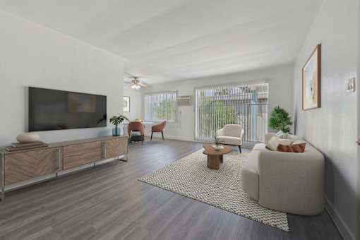 A living room with a television, a chair, a sofa, and a potted plant.