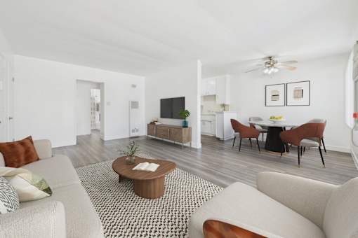 A living room with a white couch, a coffee table, and a television.
