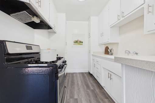 A kitchen with a black stove top oven and white cabinets.