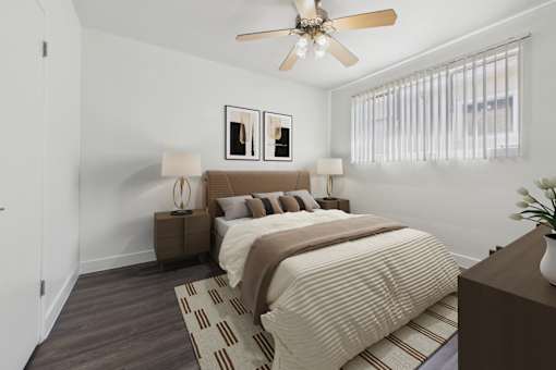 A bedroom with a bed, two lamps, a fan, and a plant.