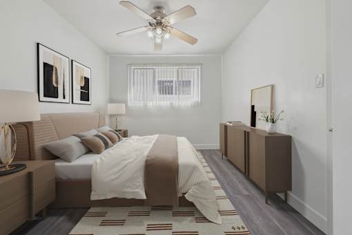 A bedroom with a bed, nightstand, and a ceiling fan.
