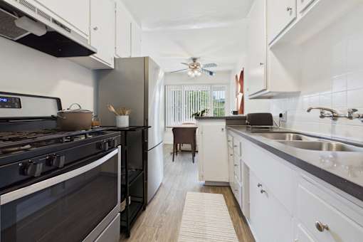 A modern kitchen with a black stove top oven and white cabinets.