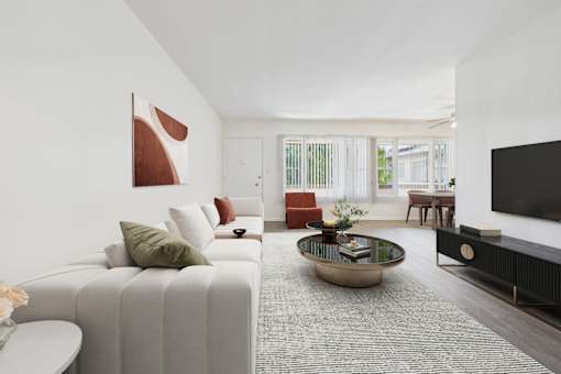 A modern living room with a white sofa, a coffee table, and a flat-screen TV.